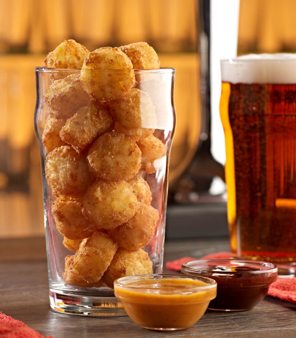 Mini Rösti Bällchen als Snack in einem Bier Glas serviert, neben soßen & Bierglas